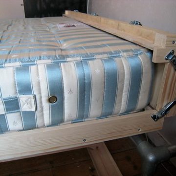 Head end of the wallbed folded up and latched round the mattress