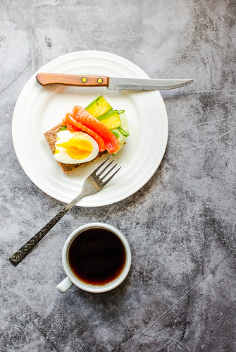 Buckwheat gluten-free bread with avocado and fresh salted salmon fillet with eggs on a gray marble background. Top view. Space for text. High protein and low carb meal