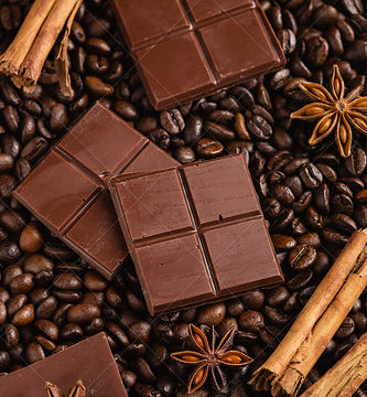 Chopped bitter chocolate with cinnamon sticks and anise stars on coffee beans background