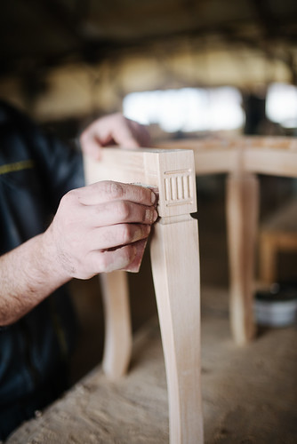 Carpenter sandpapering chair legs.