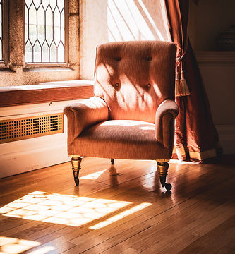 Chair Illuminated By The Morning Sunshine Casting Latice Shadows On The Wooden Floor