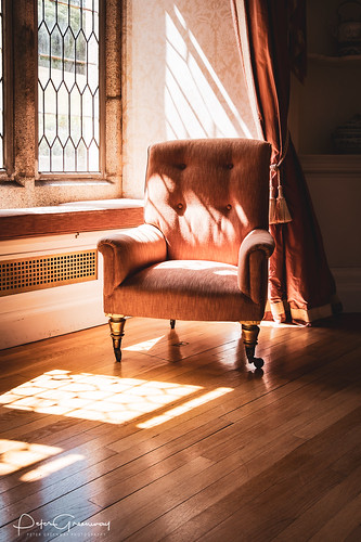 Chair Illuminated By The Morning Sunshine Casting Latice Shadows On The Wooden Floor