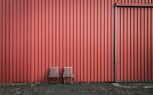 two wooden chairs in front of a red wall near Vetschau