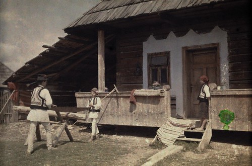 1930 - Young peasant boys saw wood outside of a farmhouse