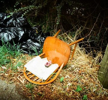 Wooden chair left for trash, and garbage bags