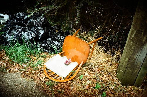 Wooden chair left for trash, and garbage bags