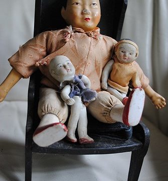 Chinese dolls sit comfortably in a black wooden chair