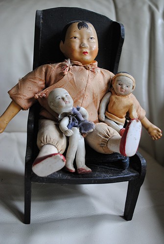 Chinese dolls sit comfortably in a black wooden chair