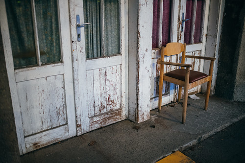 Chair in front of an old worn out wooden door. Antiqued, aged look