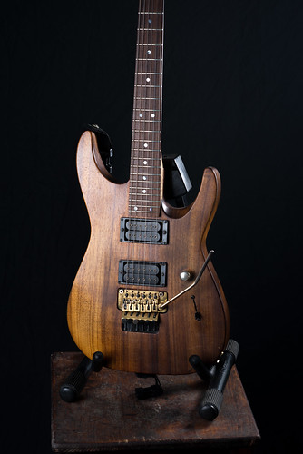 Charvel San Dimas koa on old wooden chair with a black background.