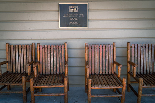 Wyoming, USA - July 18, 2022: Dedication plaque for the Old Faithful Snow Lodge hotel, with wooden chairs outside