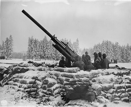 Gun crew of the ‘Black Widow’, 90 mm anti-aircraft gun dug in outside Bastogne, Belgium, about to fire at enemy plane sighted in area. Battery B 217th Bn (Radar) Bastogne.